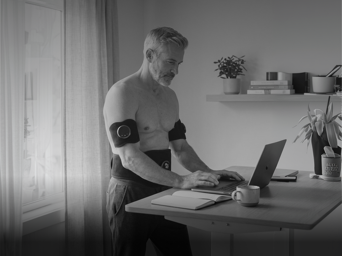A man seated on a sofa wearing the belt and two arm units